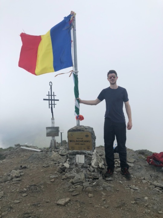 Iain stood with his hand on the Romanian flag at the summit of Moldoveanu mountain.