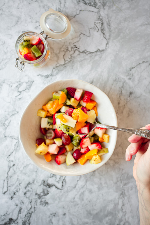 hand lifting a spoon of Summer Fruit Salad