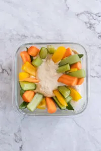 Homemade Hummus Recipe With Veggie Sticks in storage container.