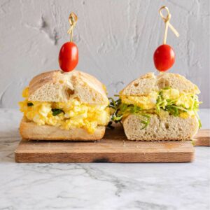 Egg salad sandwich cut into two halves and presented on a chopping board
