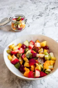 A selection of summer fruits diced and mixed within a bowl and presented on a kitchen surface