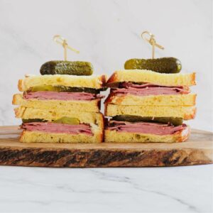 Montreal smoked meat sandwich cut into two halves and presented on a chopping board