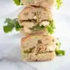 Two halves of a tuna salad sandwich stacked on top of each other and presented