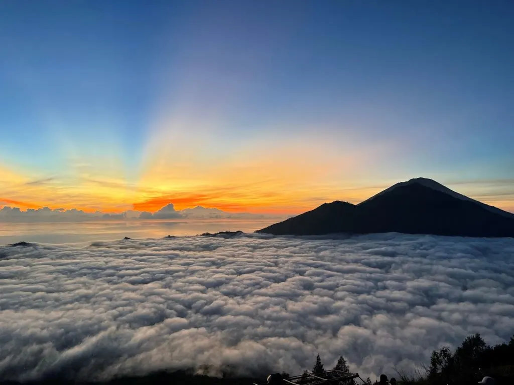 Mount Agung is seen rising through the clouds at sunrise