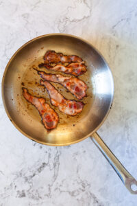 bacon strips being cooked in a skillet