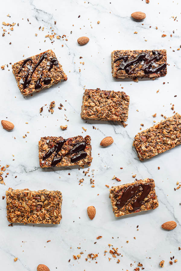 Homemade Granola Bars arranged on a surface with melted chocolate drizzled on top