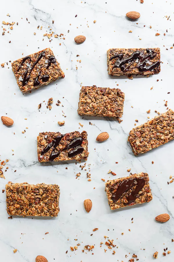 Homemade Granola Bars arranged on a surface with melted chocolate drizzled on top