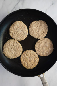 cooking the sausage patties in a non stick pan for the make ahead breakfast burritos